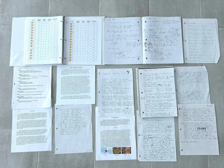 Collection of handwritten and printed notes, worksheets, and scrap paper spread out on a tile floor.